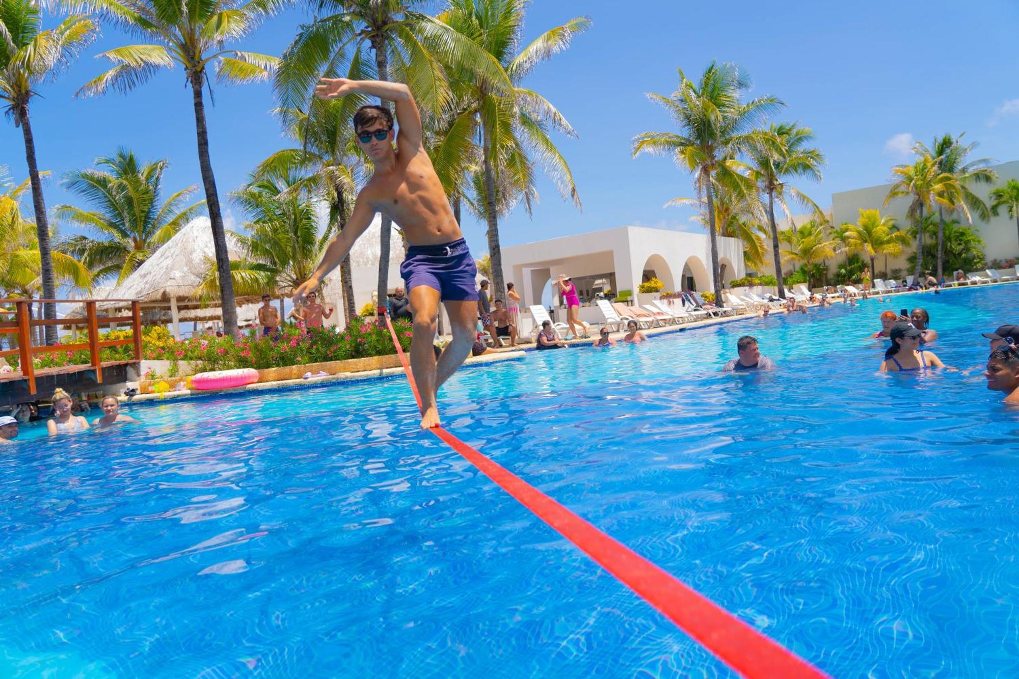 Grand Oasis Cancun Hotell Exteriör bild A man walking on a slackline over a pool